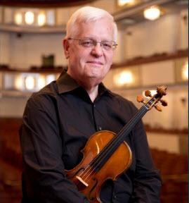 Violinist Peter Haase holding his violin in a concert hall